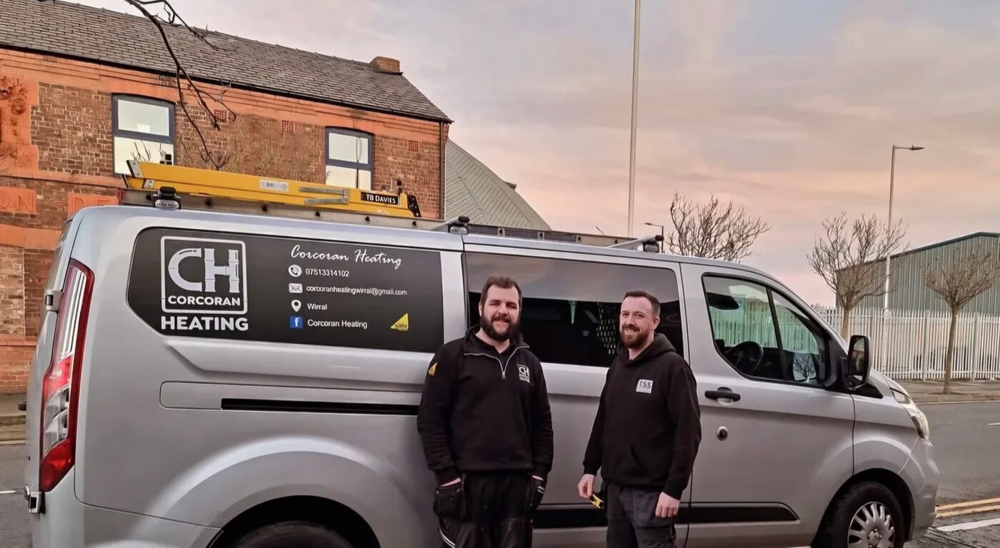 Pete standing beside a customer and a Corcoran Heating van with completed vehicle graphics in 2023